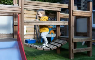 nursery child on bridge of climbing equipment in garden of monkey puzzle altrincham